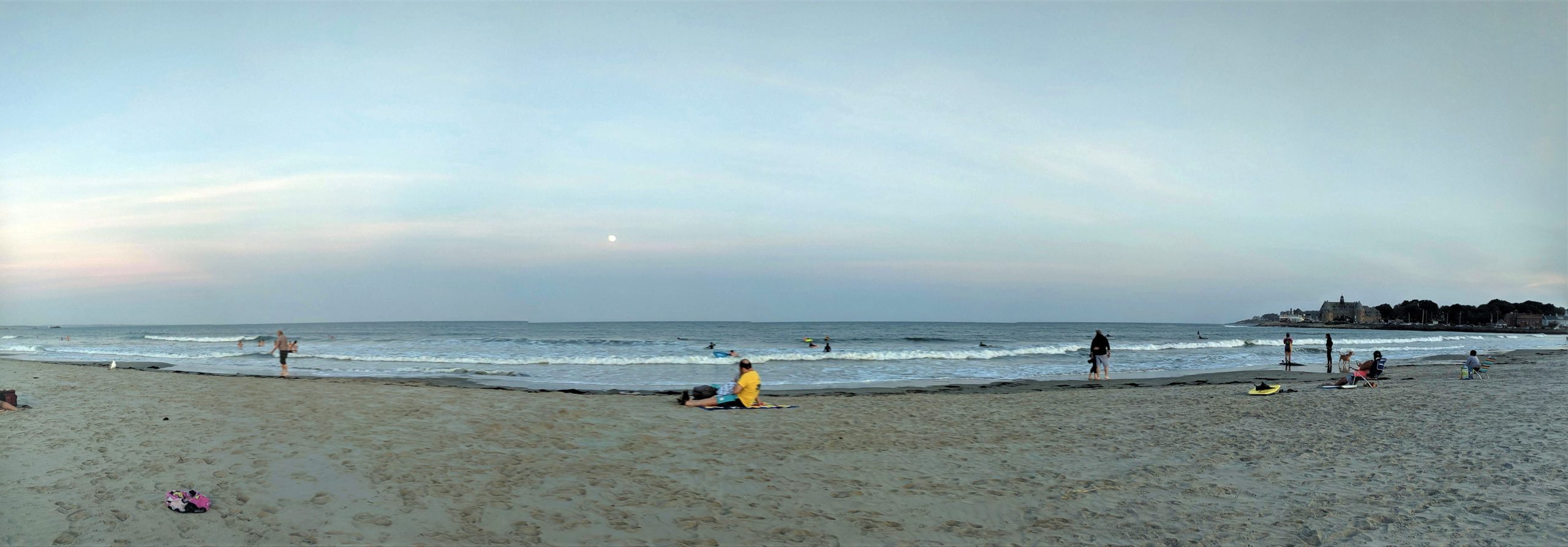 public beach in evening with moon rising over ocean